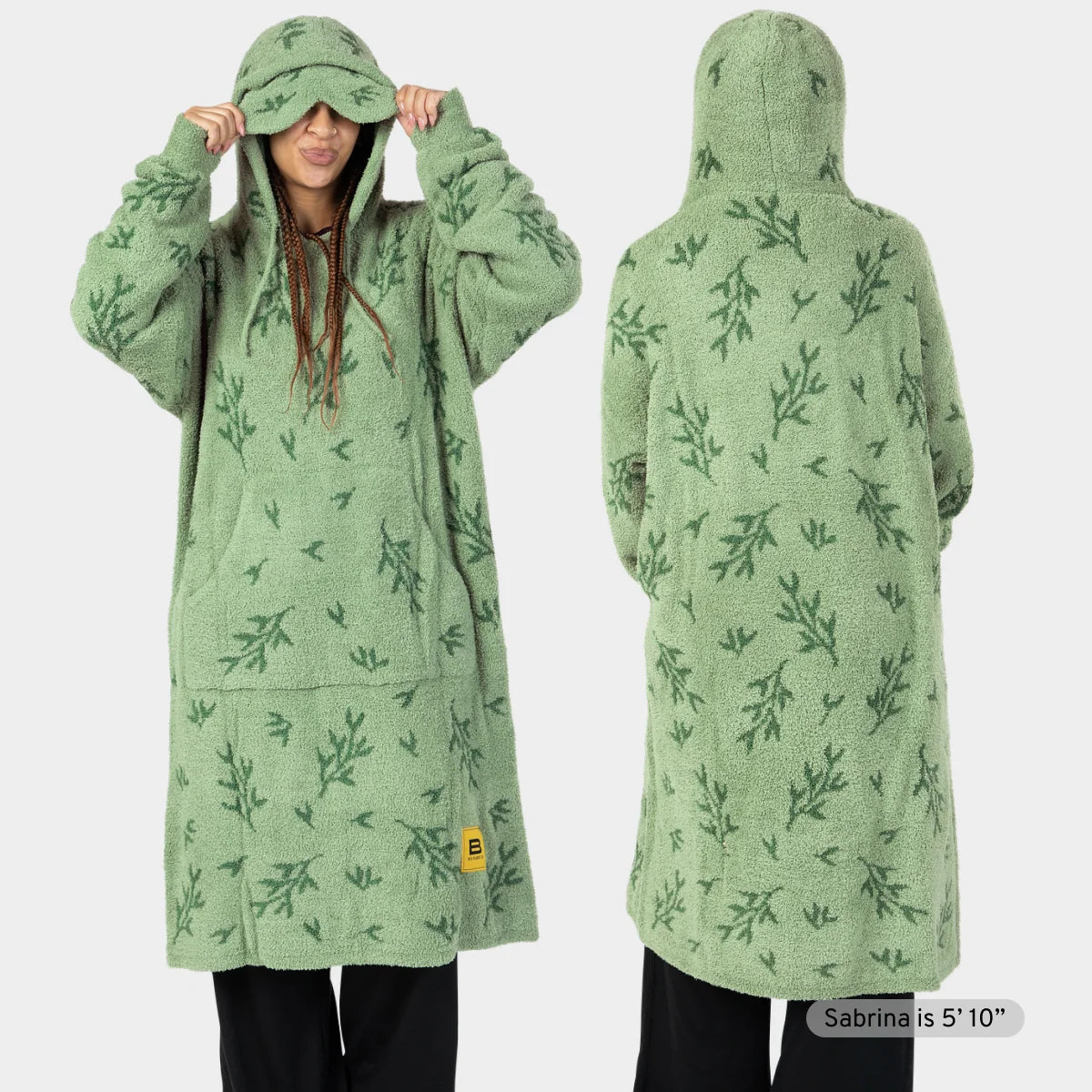 Sage green oversized hoodie blanket with fern leaf pattern, worn by model as full-length robe with attached hood