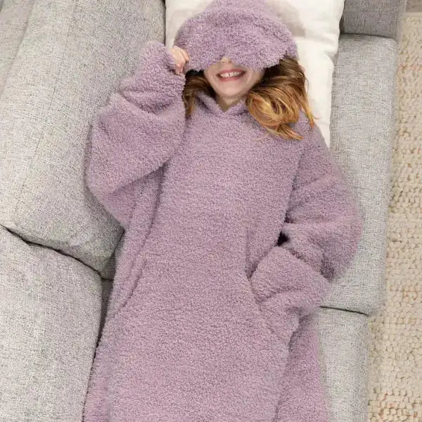 Child wrapped in lavender Premier Plush Hoodie on bed, cozy oversized blanket with hood covering face