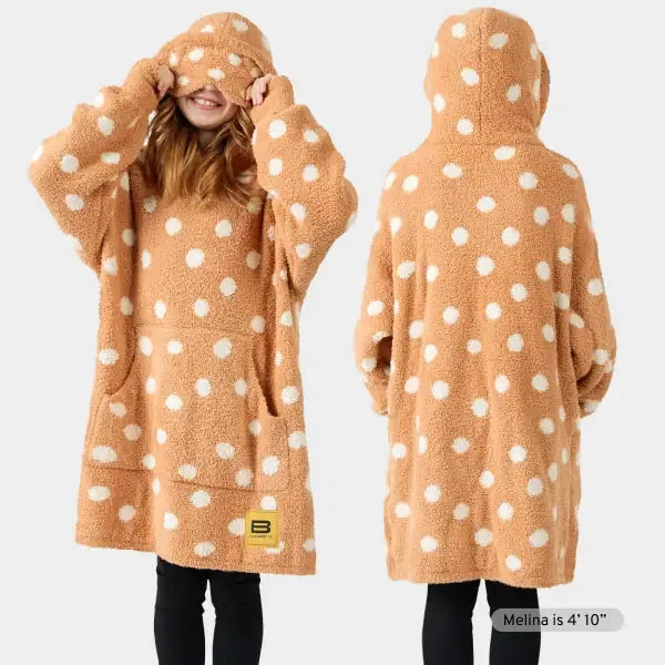 Tan oversized hoodie blanket with white polka dots, shown front and back on model wearing black pants