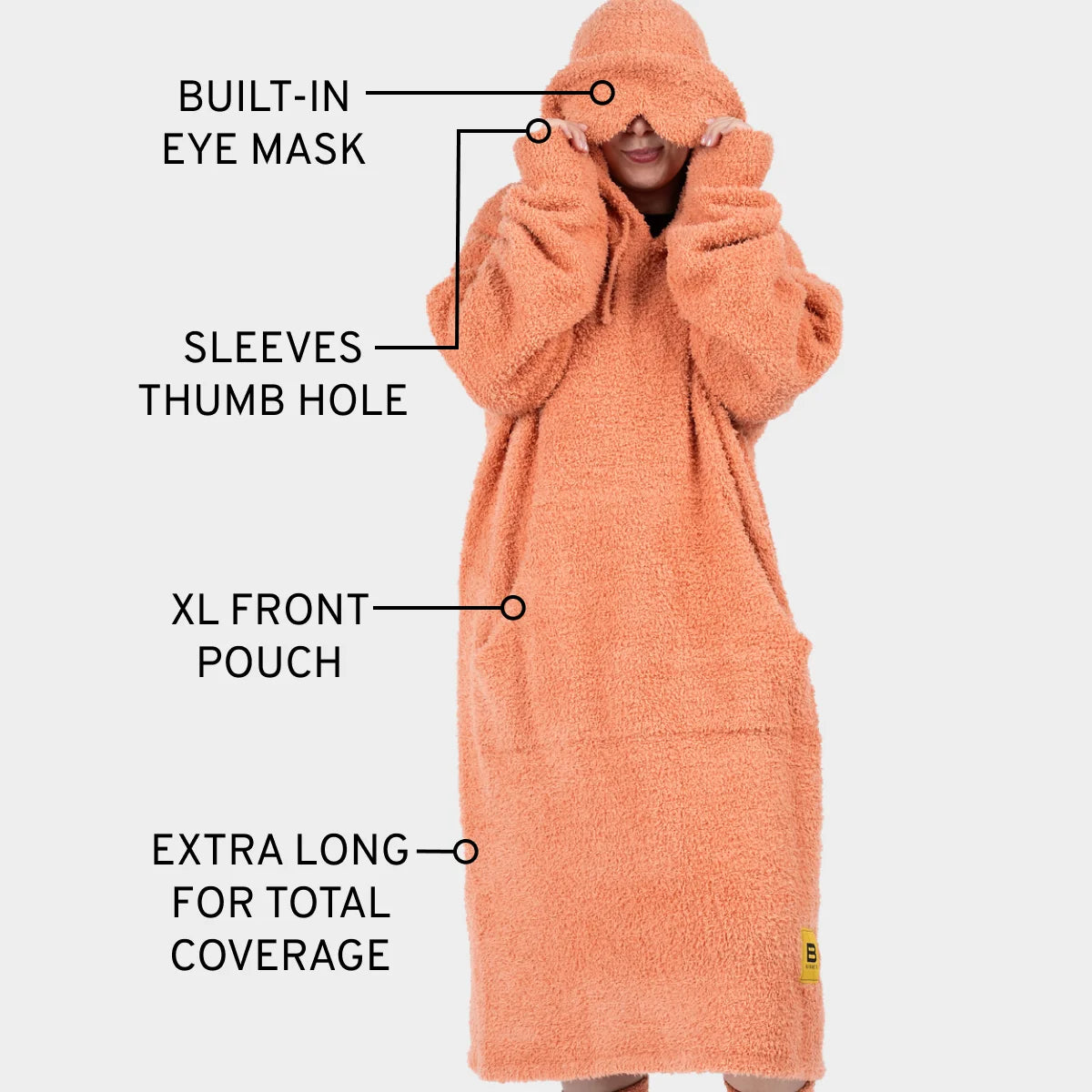 Coral oversized hoodie blanket with built-in eye mask, thumb hole sleeves, and XL front pouch, modeled full-length