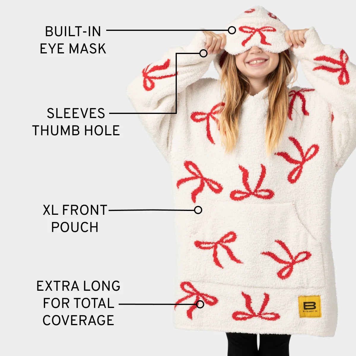 Cream oversized hoodie blanket with red bow pattern, featuring built-in eye mask, thumb holes, and XL front pouch