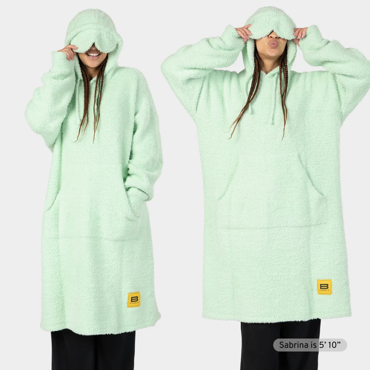 Child wearing mint green oversized hoodie blanket with front pocket and hood pulled over head
