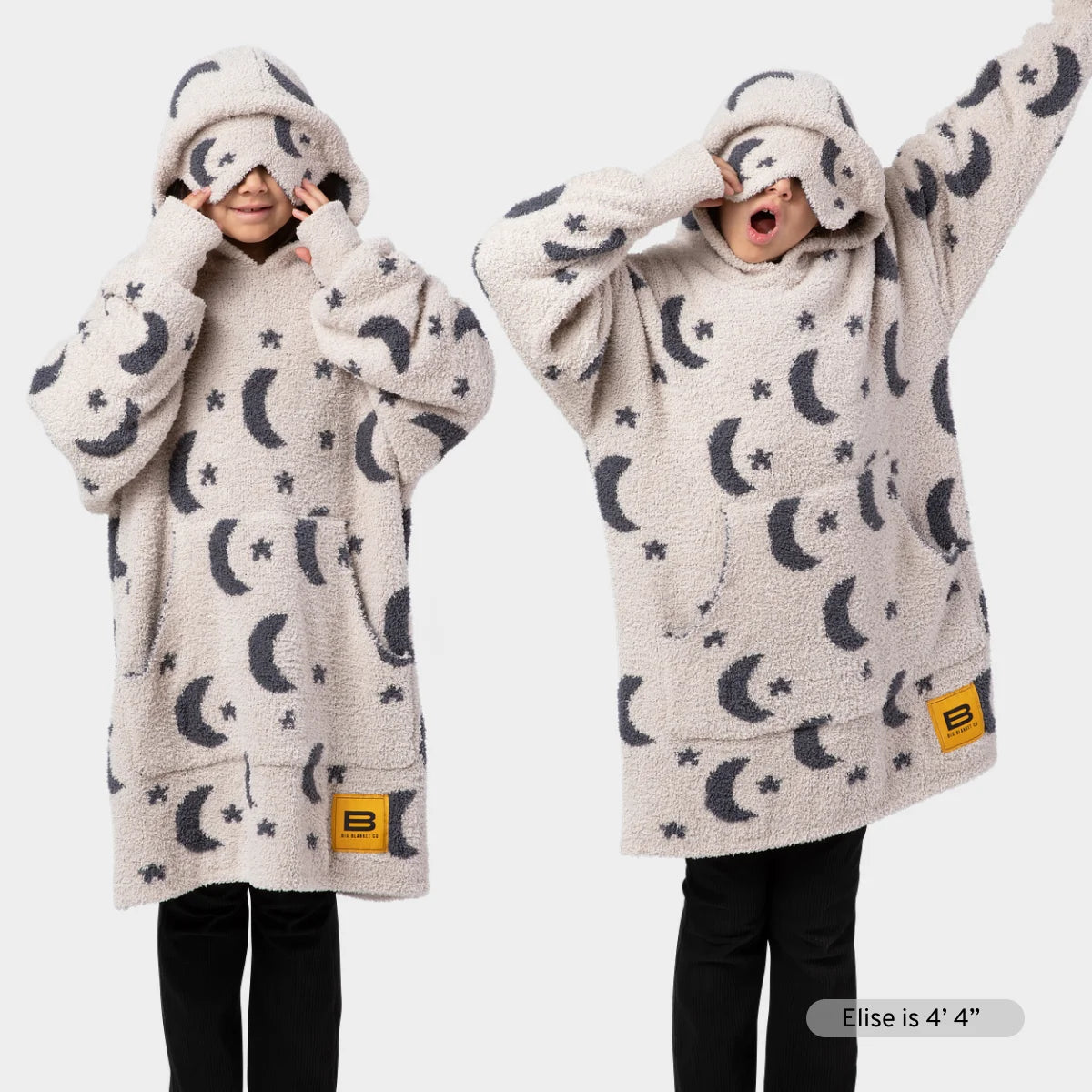 Kids wearing cream Premier Plush Hoodie with navy moon and star pattern, hood up with matching design