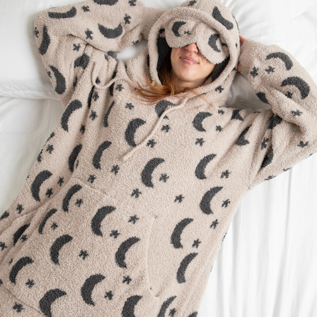 Child wearing cream Premier Plush™ Hoodie with moon and stars pattern, built-in eye mask, thumb hole sleeves, XL front pouch, extra-long coverage