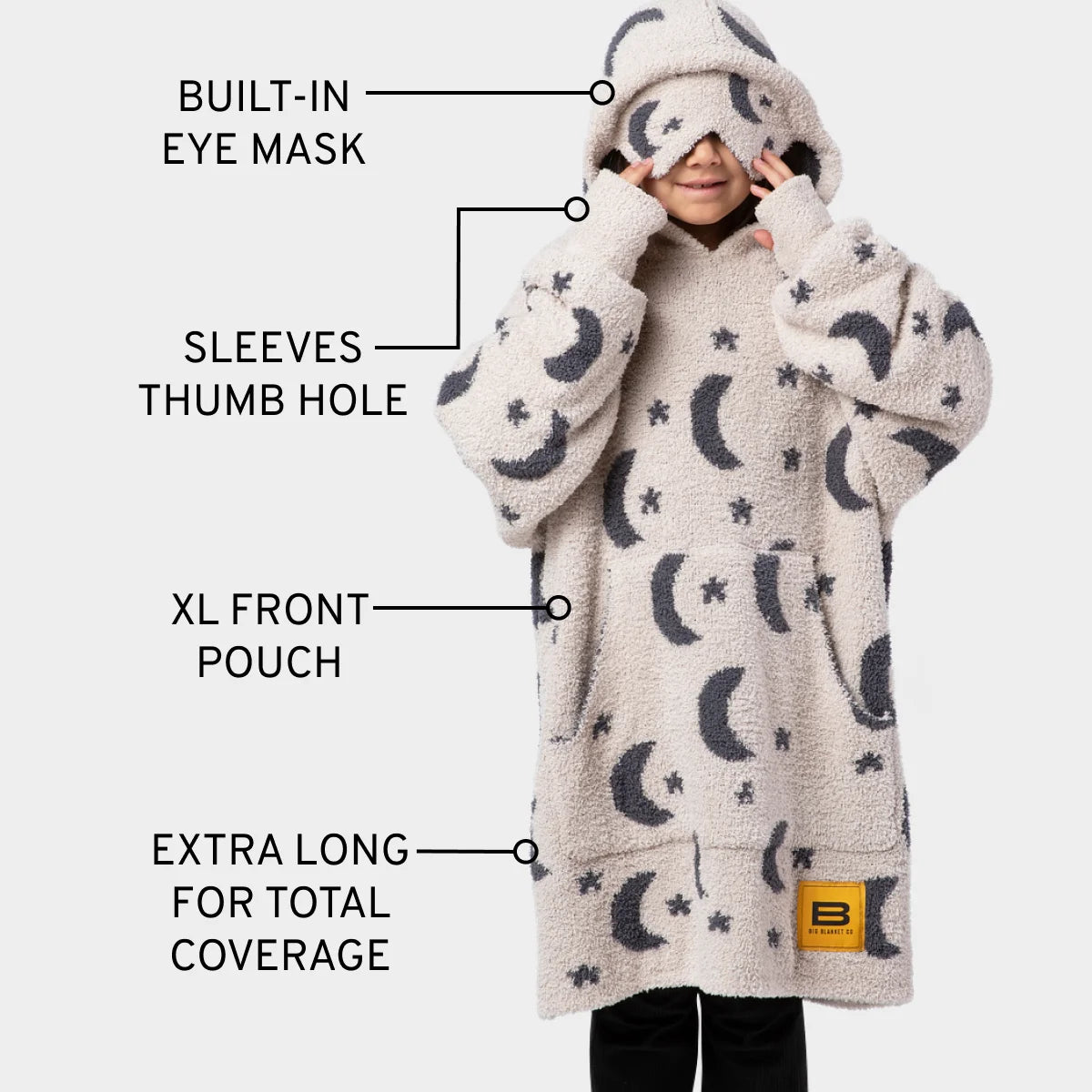 Child wearing cream oversized hoodie blanket with moon and star pattern, built-in eye mask and sleeves with thumb holes