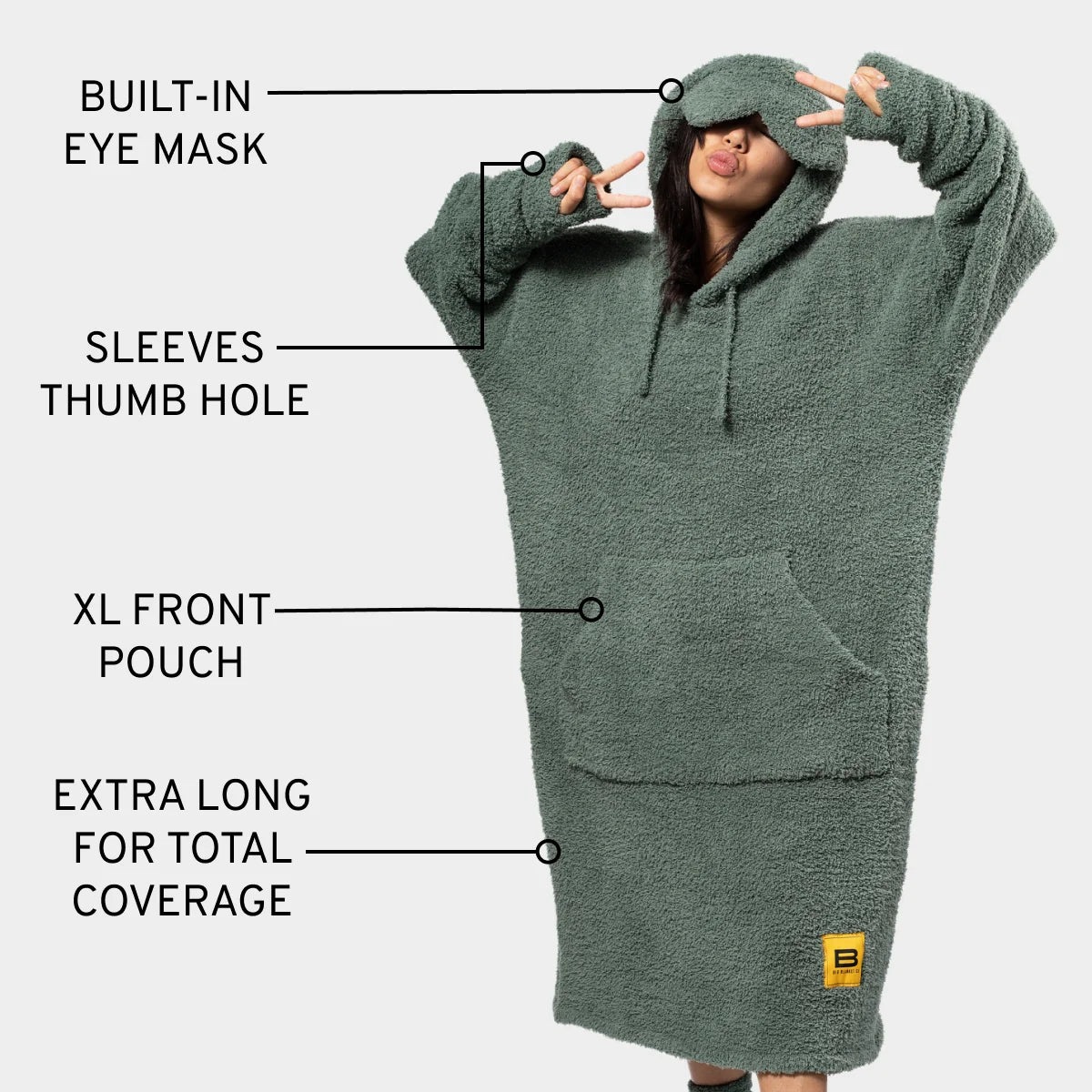 Moss green oversized hoodie blanket with built-in eye mask, thumb holes, and XL front pouch worn by woman