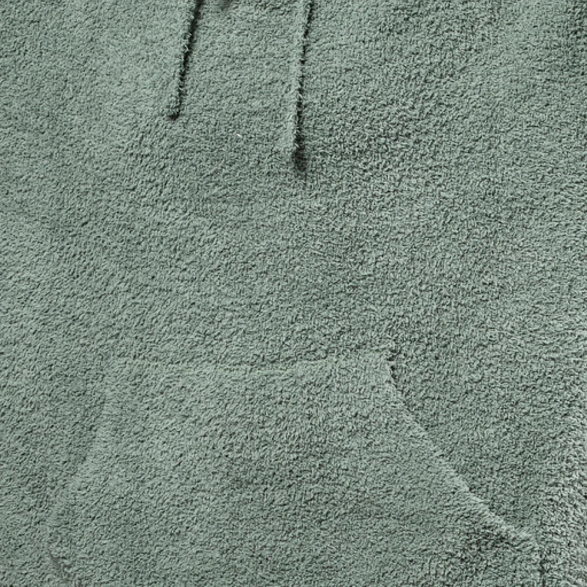 Sage green oversized blanket with soft plush texture and vertical seams, folded detail visible