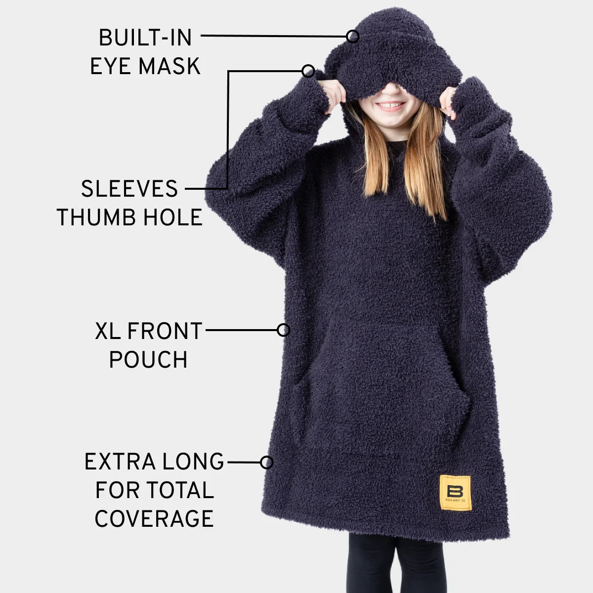 Man wearing navy oversized wearable blanket hoodie with built-in eye mask, thumb hole sleeves, XL front pouch, and extra long coverage