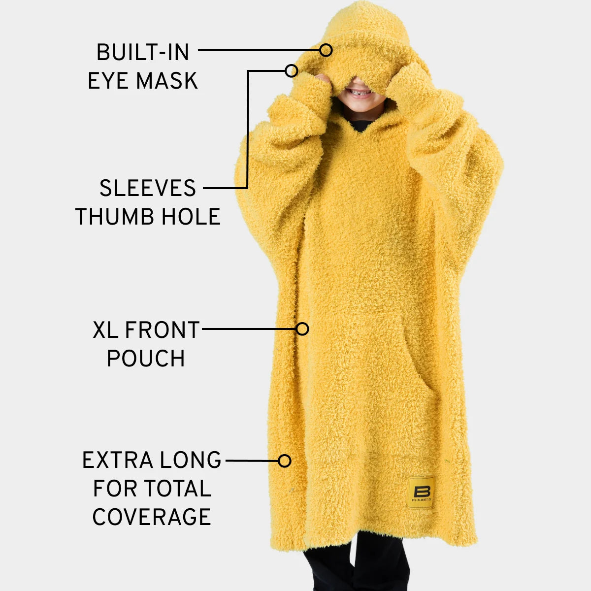 Yellow oversized blanket hoodie with built-in eye mask, thumb holes, front pouch, and extra-long coverage shown on smiling child model
