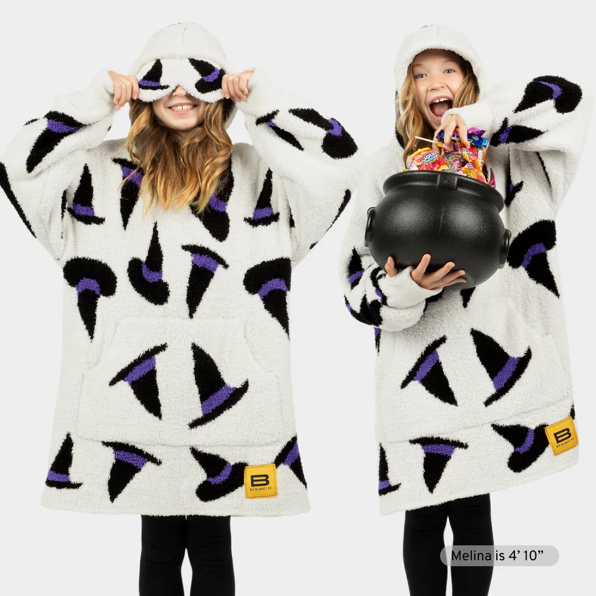 Woman wearing cream oversized hoodie blanket with black and purple witch hat pattern, matching eye mask, and hood pulled up