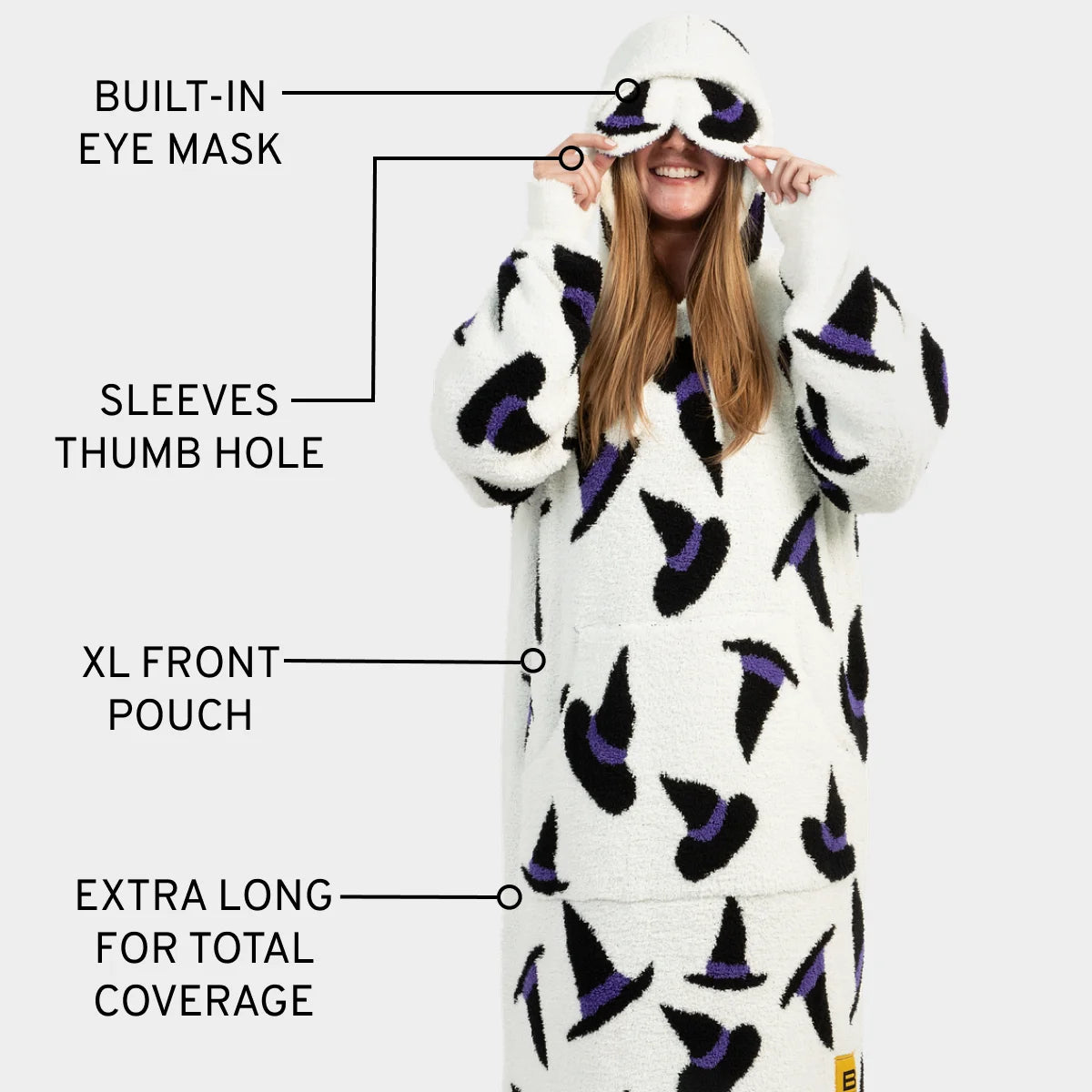 Woman wearing cream Premier Plush hoodie with purple and black witch hat pattern, featuring built-in eye mask, thumb hole sleeves, and XL front pouch