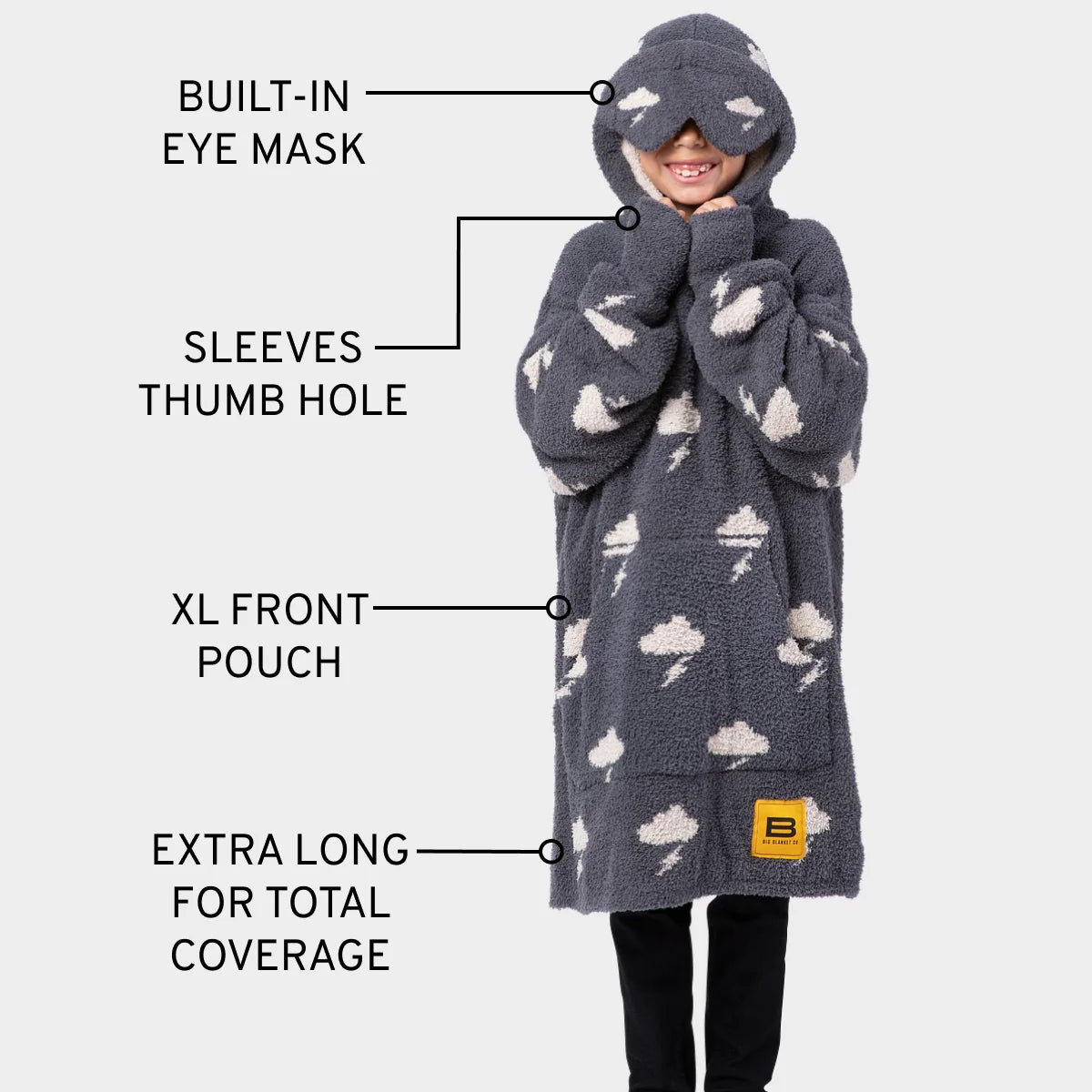 Child wearing dark gray oversized hoodie blanket with cloud and lightning pattern, built-in eye mask, sleeve thumb holes, and front pouch