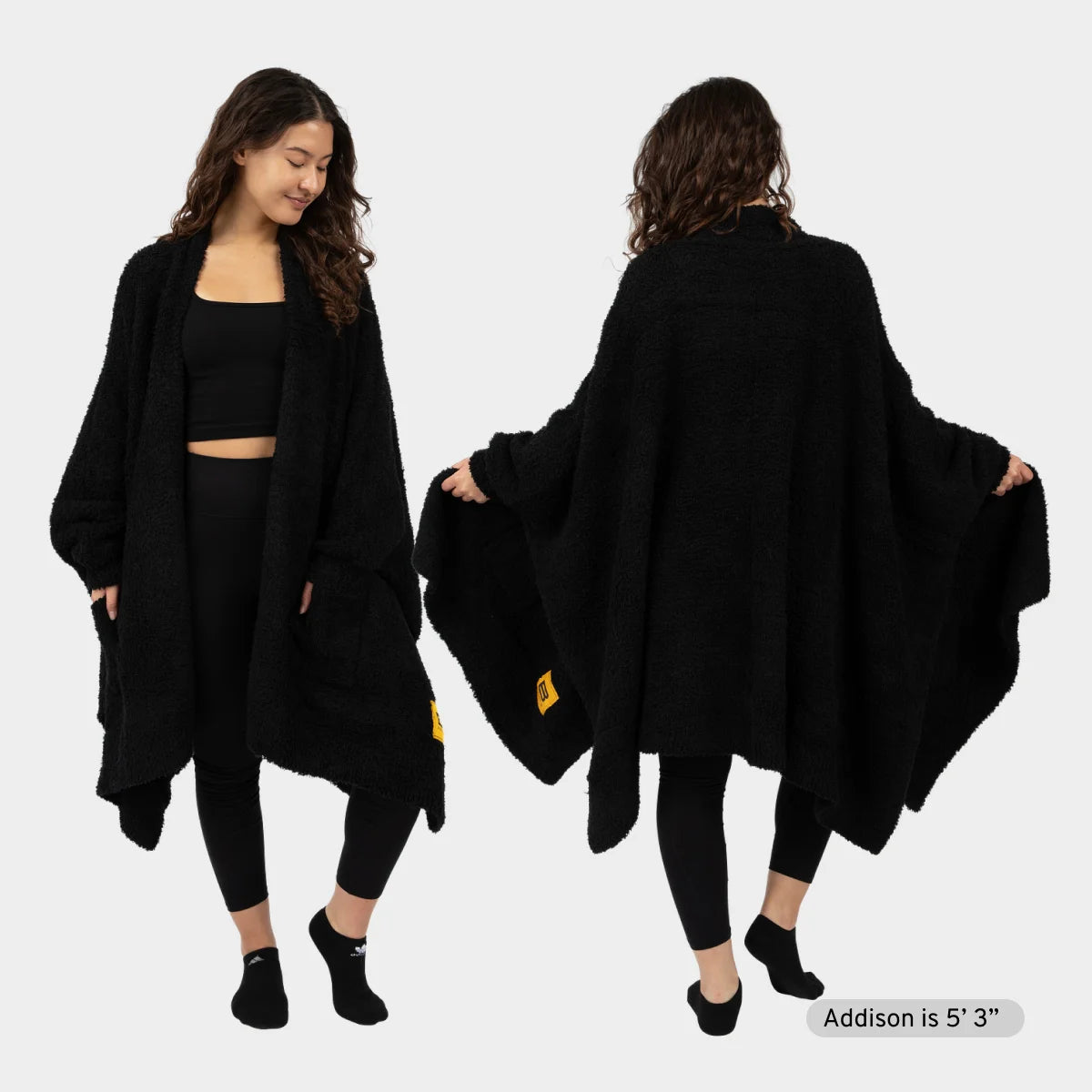 Woman wearing black Premier Plush™ Wrap oversized blanket shawl, front and back view, with gold Big Blanket Co logo