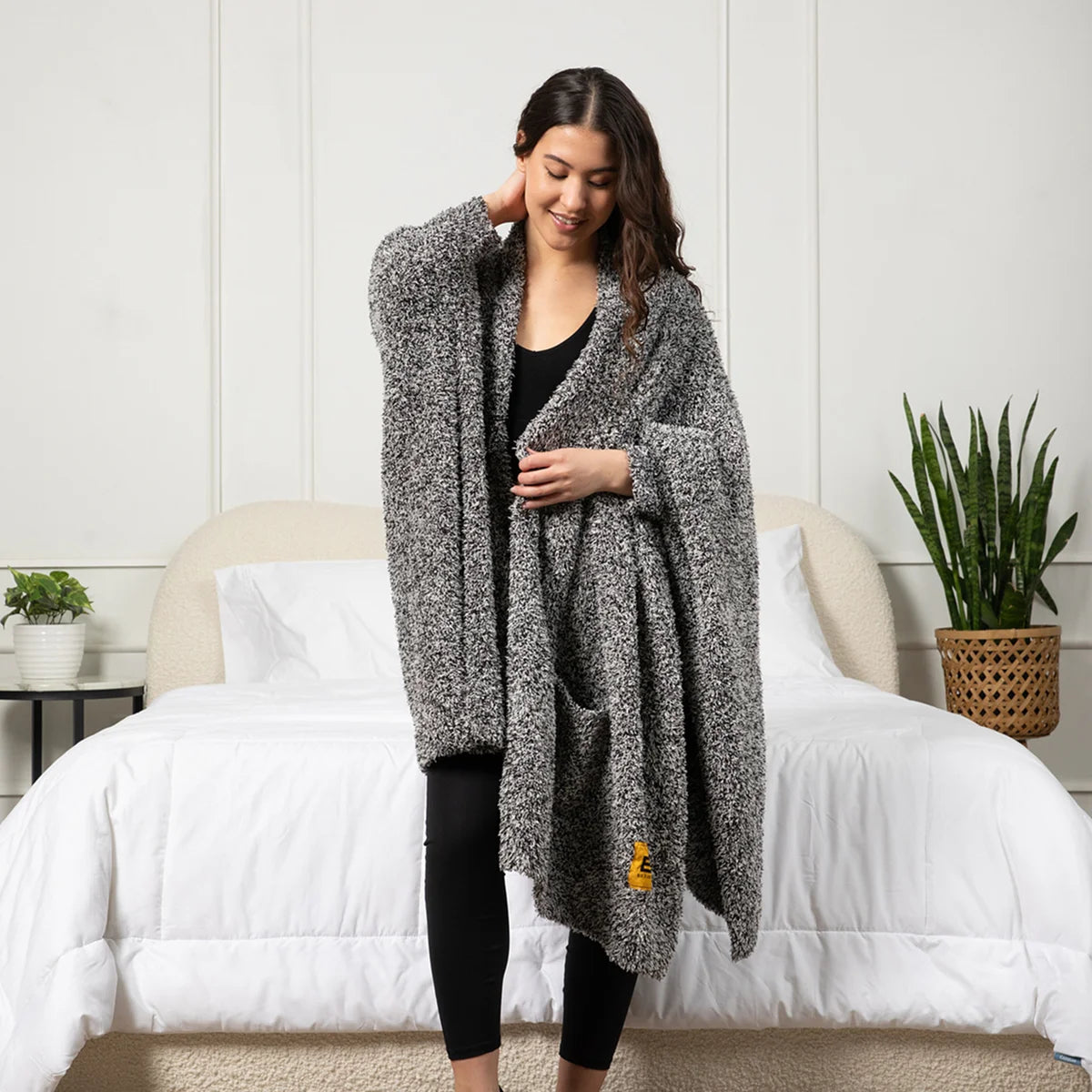 Woman wearing charcoal heather oversized blanket wrap draped over shoulders on bed