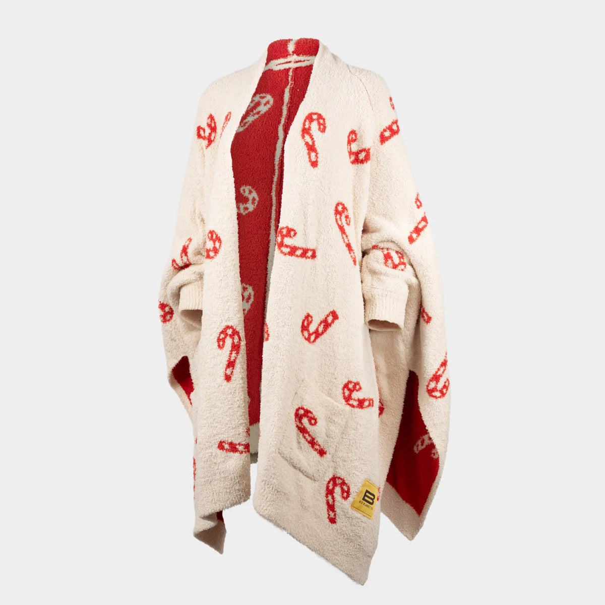 Cream oversized blanket wrap with red candy cane pattern, burgundy reverse side, draped on figure with pockets visible