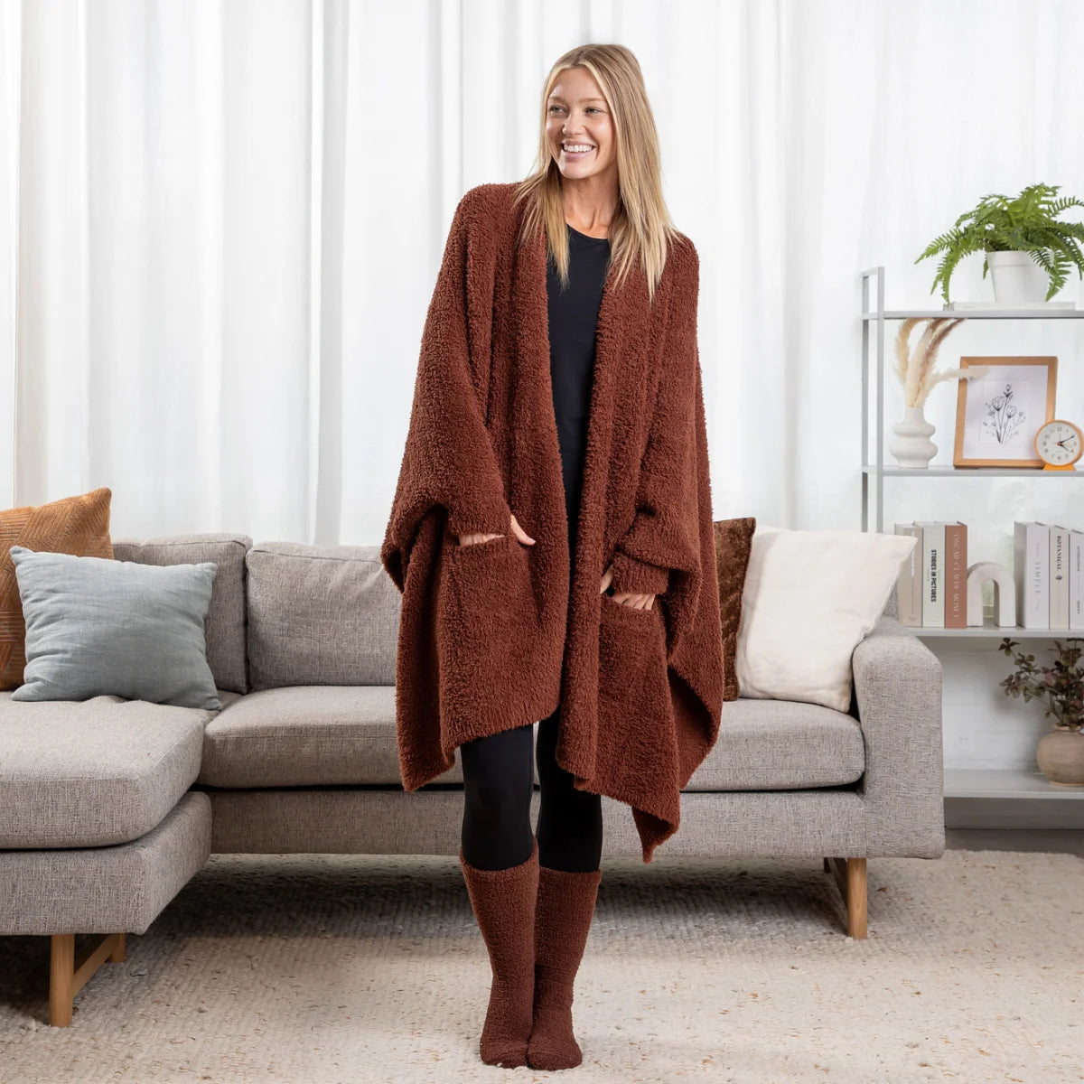 Woman wearing chocolate Premier Plush wrap draped oversized around shoulders, standing in living room