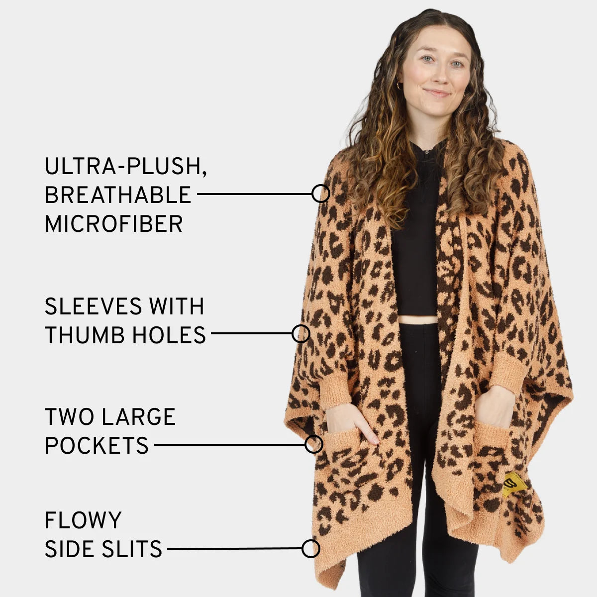 Woman wearing tan leopard print oversized blanket wrap with thumb holes, pockets, and side slits