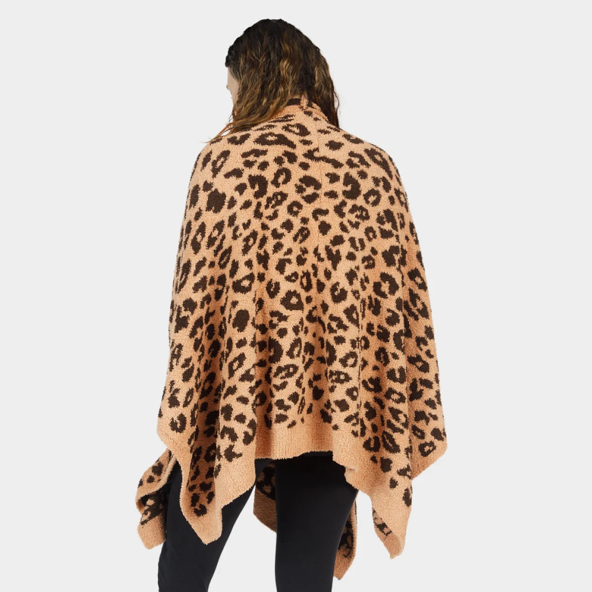Leopard print oversized wrap in tan and black worn over shoulders, showcasing soft plush texture and draped design