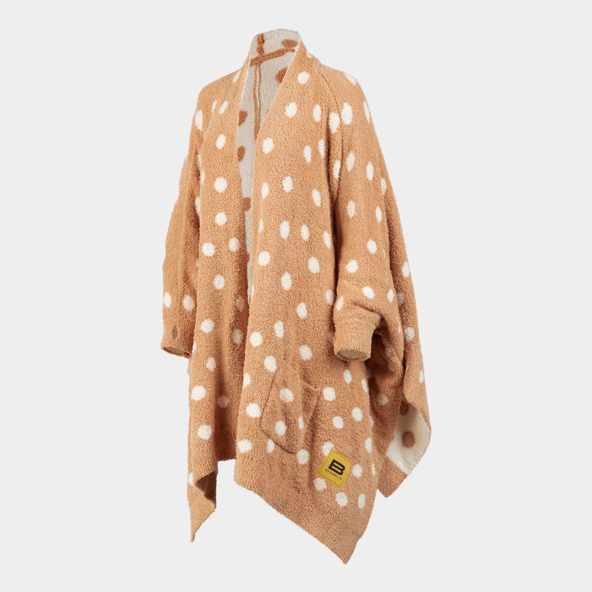 Tan oversized blanket wrap with white polka dots and cream reverse side, displayed on stand