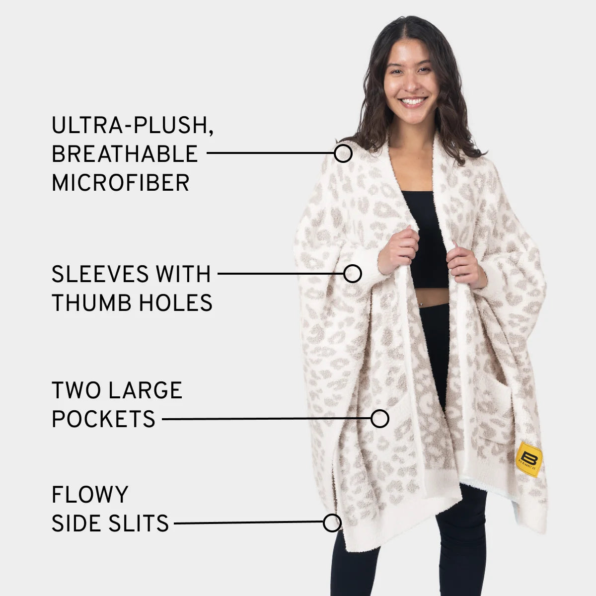 Woman wearing cream leopard print oversized blanket wrap with sleeves, thumb holes, pockets and side slits