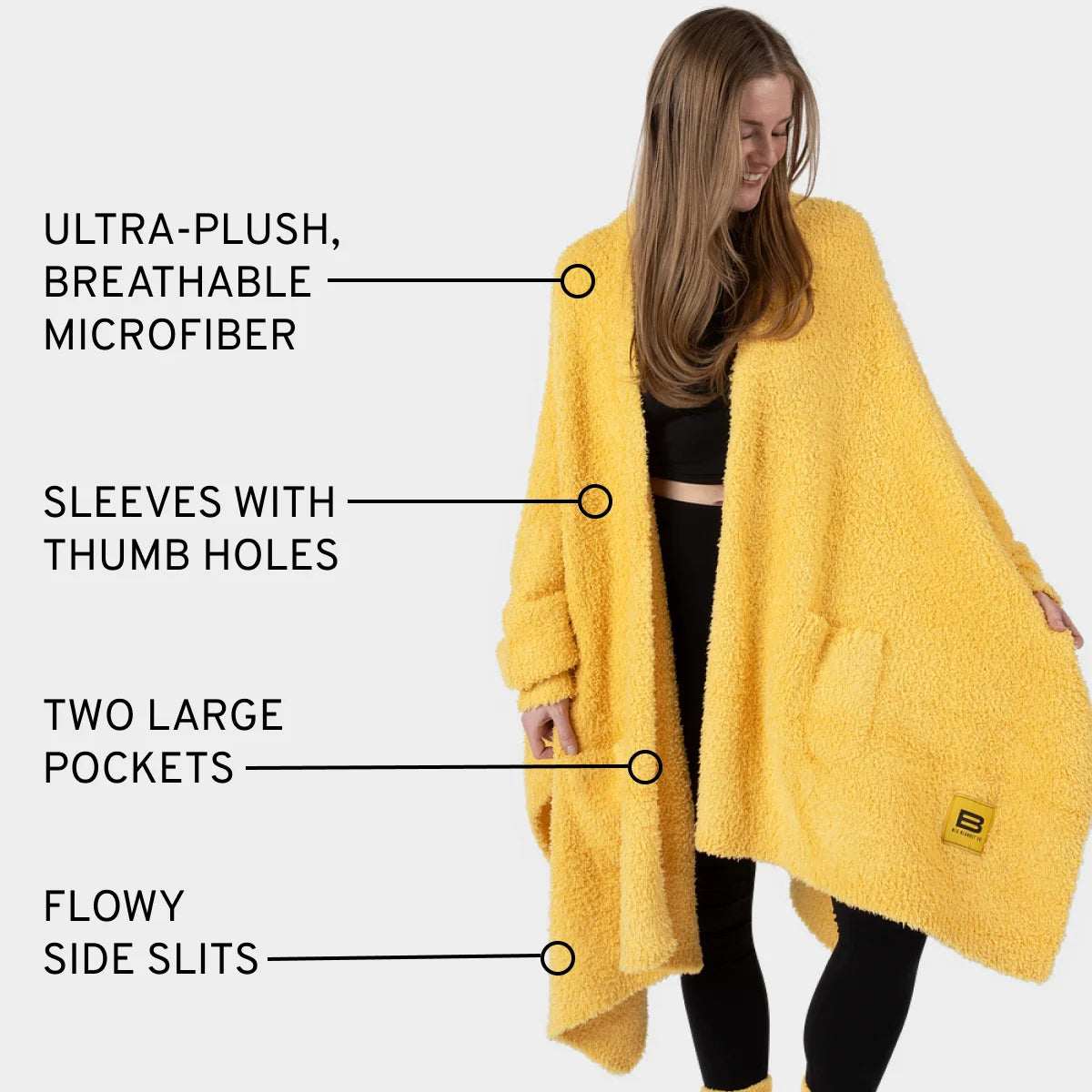 Woman wearing sunflower yellow oversized plush wrap with sleeves, thumb holes, pockets, and side slits
