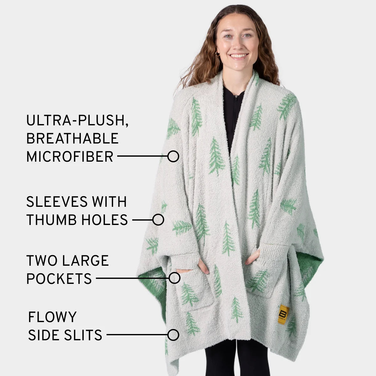Woman wearing cream and green tree-patterned oversized blanket wrap with thumb holes and pockets