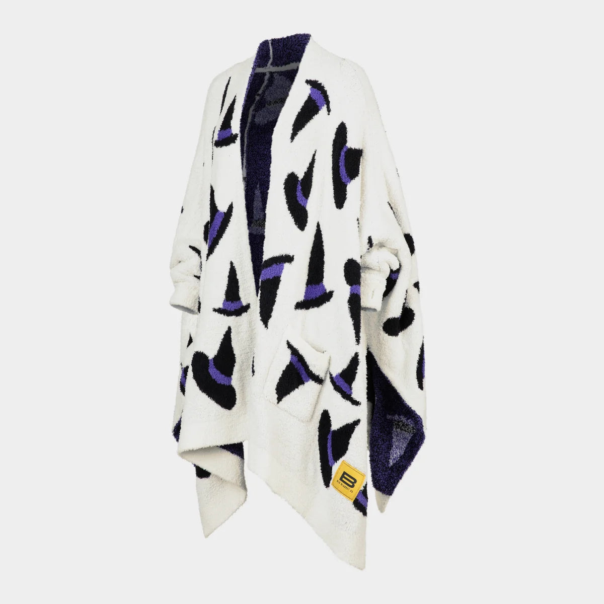 Cream oversized blanket wrap with black and purple abstract witchy pattern, draped on figure with navy reverse side visible