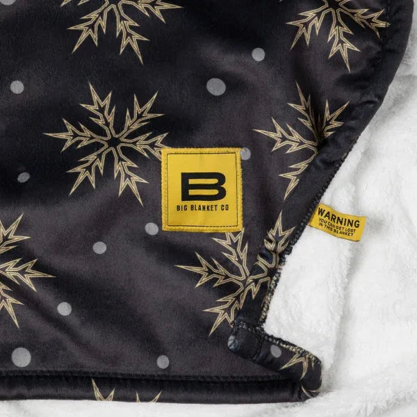 Black oversized blanket with gold snowflake pattern, white sherpa backing, Big Blanket Co label visible