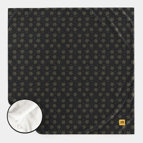 Charcoal oversized blanket with gold snowflake pattern, showing soft white sherpa reverse side in inset circle
